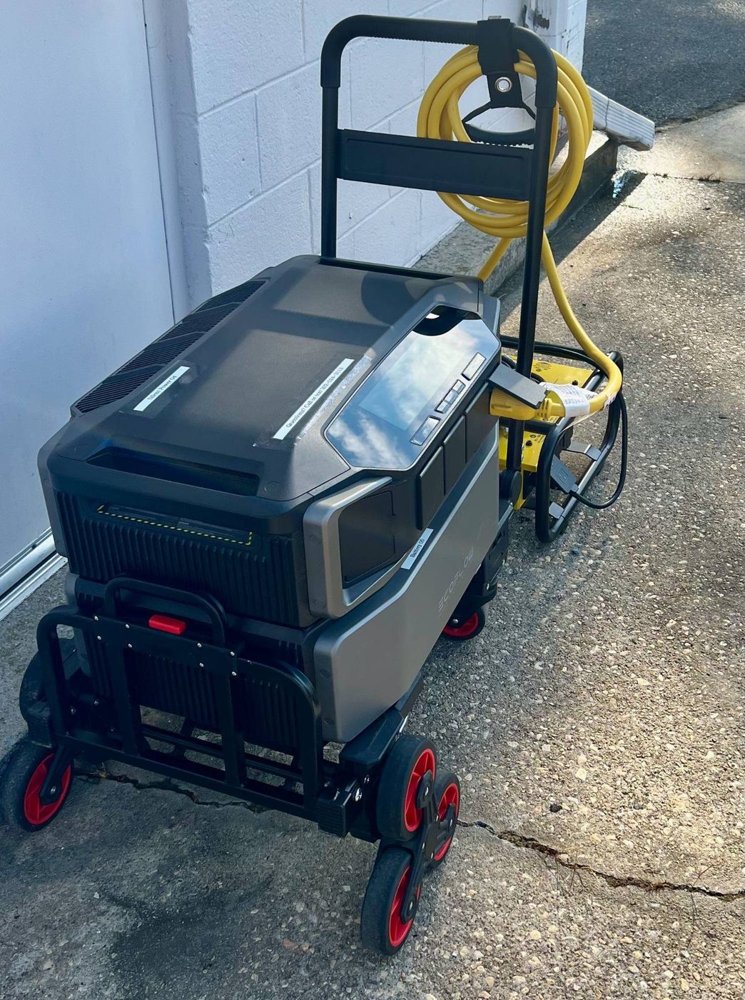 Close-up of the EcoFlow DELTA Pro Ultra inverter and battery on the wheeled cart, plugged into the Champion Pro power distribution unit via a yellow 50-amp cable